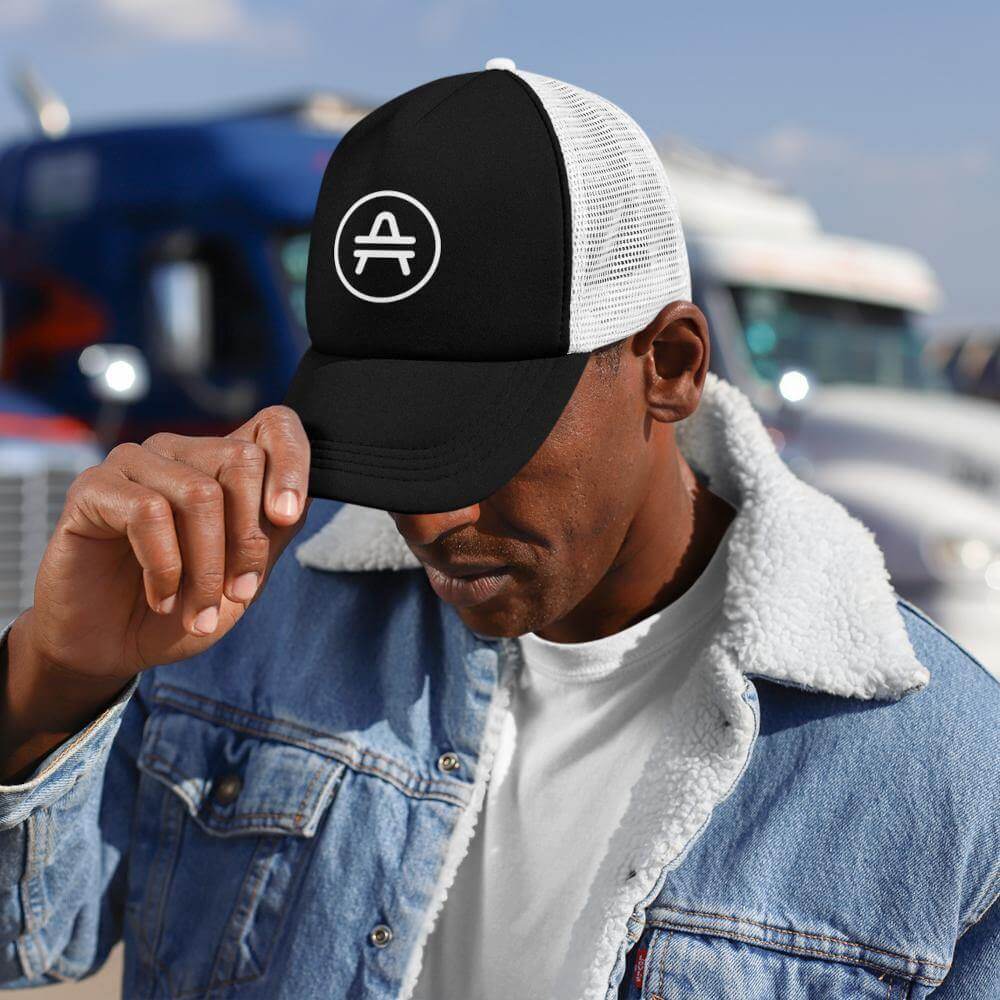 A guy wearing a black and white AMP Token AMP swagg alt-logo Trucker hat